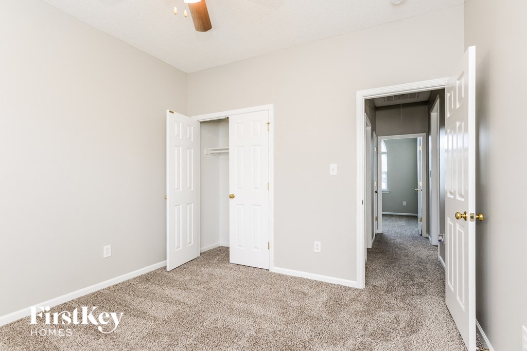a bedroom with two closets and a carpeted floor and a hallway with doors