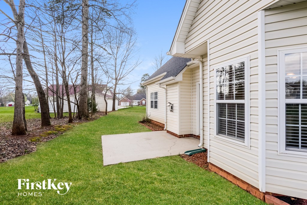 a side view of a white house with a concrete walkway next to it