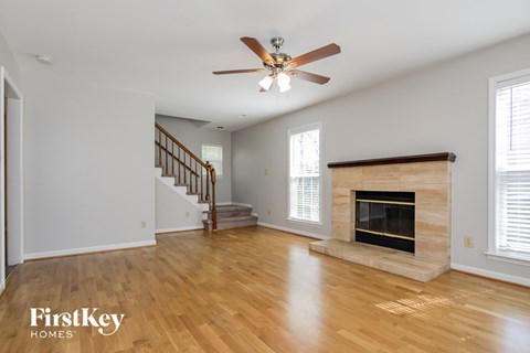 A spacious living room with a fireplace and a staircase.