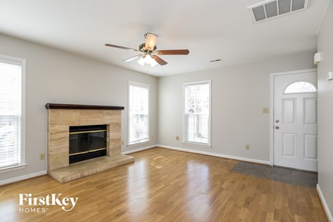 A spacious room with a fireplace and a ceiling fan.