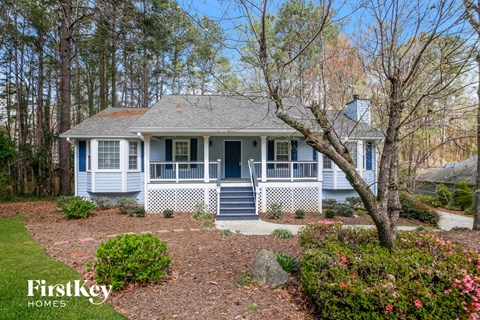 a blue and white house with a yard and trees