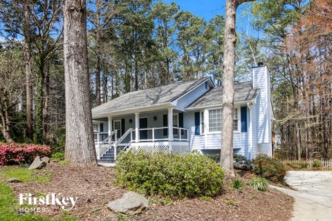 a small blue house with a porch in the woods