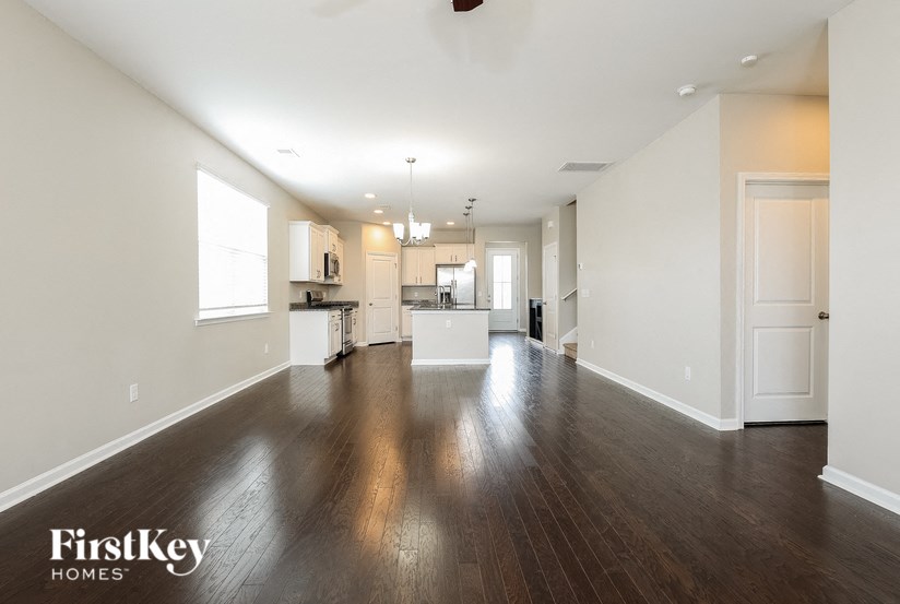 an empty living room and kitchen with wood floors