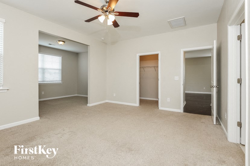an empty living room with a ceiling fan and a closet
