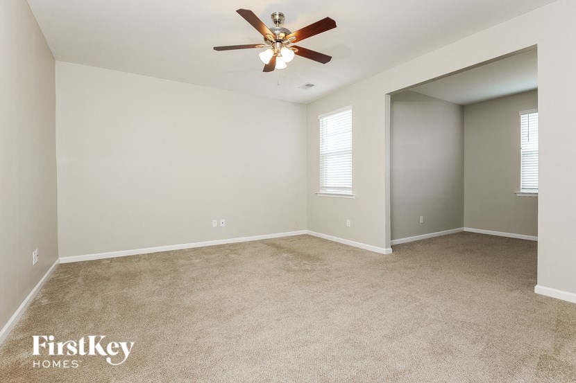 an empty living room with a ceiling fan