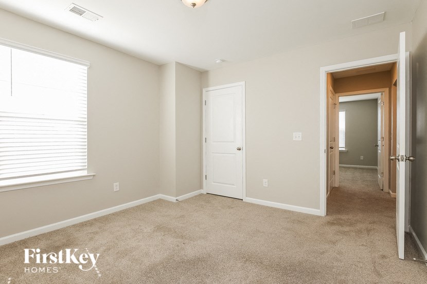 a bedroom with a door to a hallway and a carpeted floor