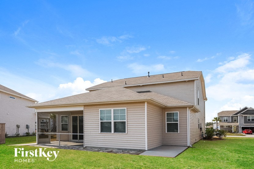 a small tan house with a yard and a blue sky
