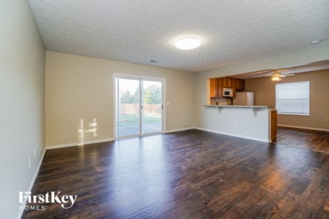 the living room and kitchen of an empty house with wood flooring