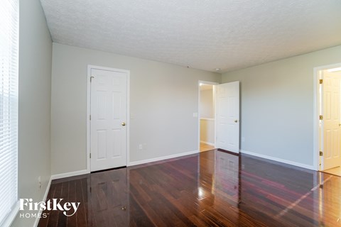 a living room with wood floors and white walls and two doors