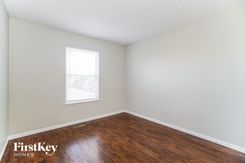 a bedroom with wood floors and white walls and a window