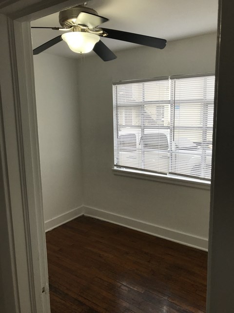 an empty bedroom with a ceiling fan and a window