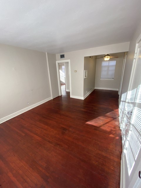 an empty living room with wood floors and a window