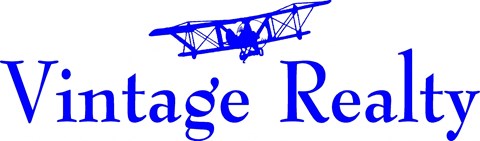 A blue and white sign for Vintage Realty with an airplane graphic.
