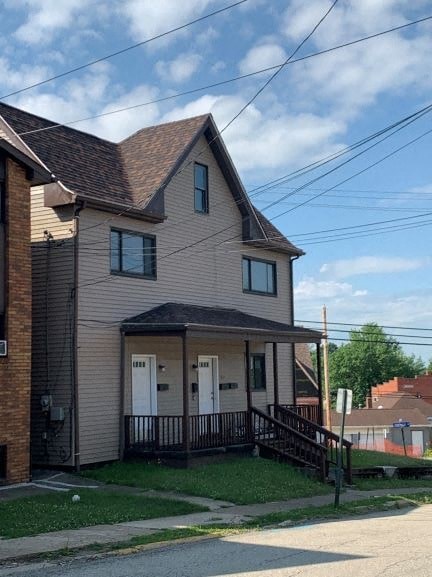 A house with a brown roof and a grey siding with a black railing.