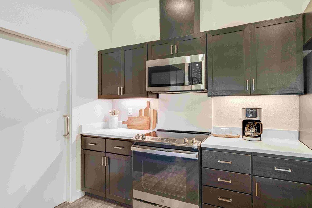 a kitchen with black cabinets and a stove and a microwave