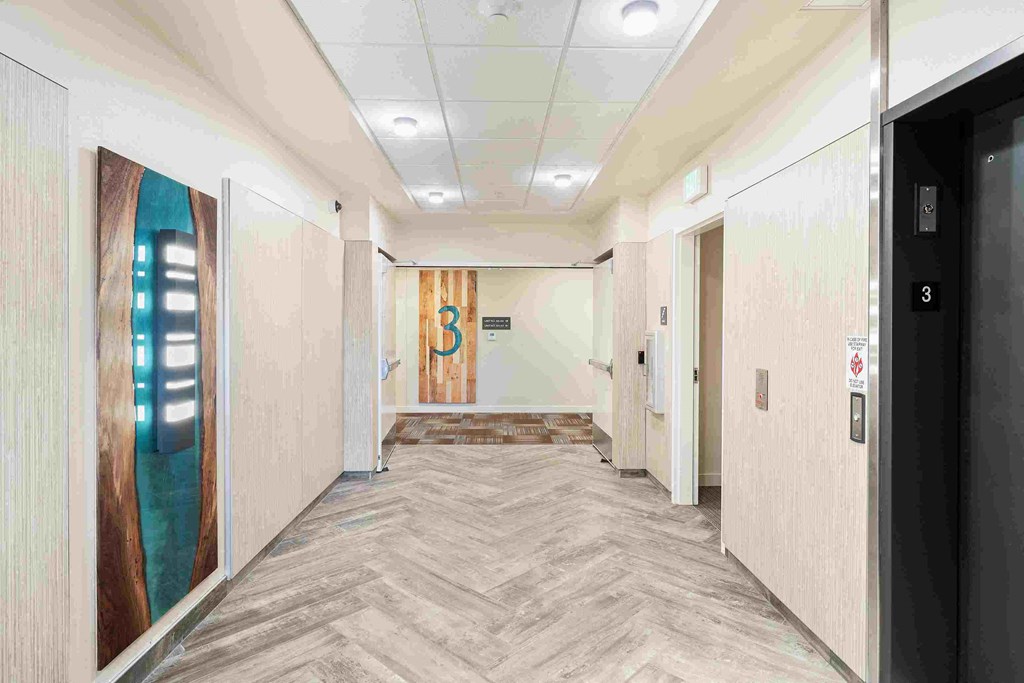 a hallway with doors in a building with wood floors and white walls