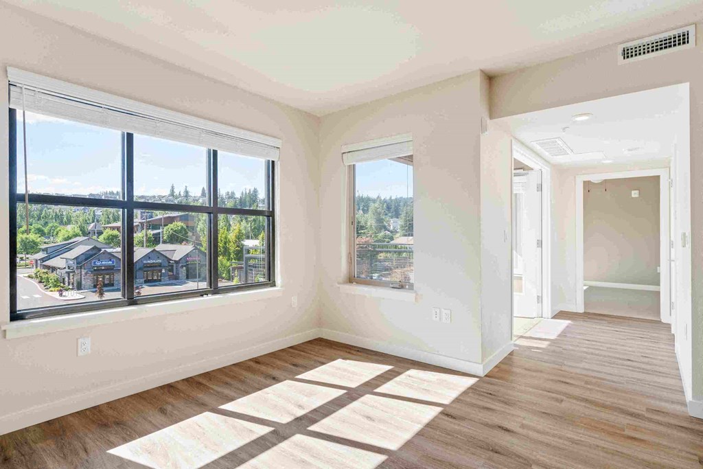 an empty living room with large windows and wood floors