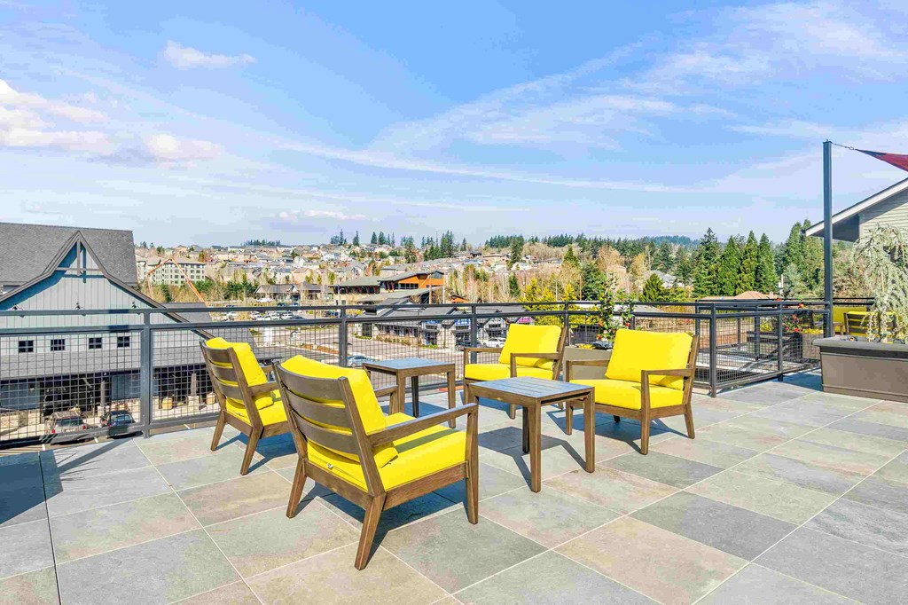 a patio with yellow chairs and tables on top of a roof