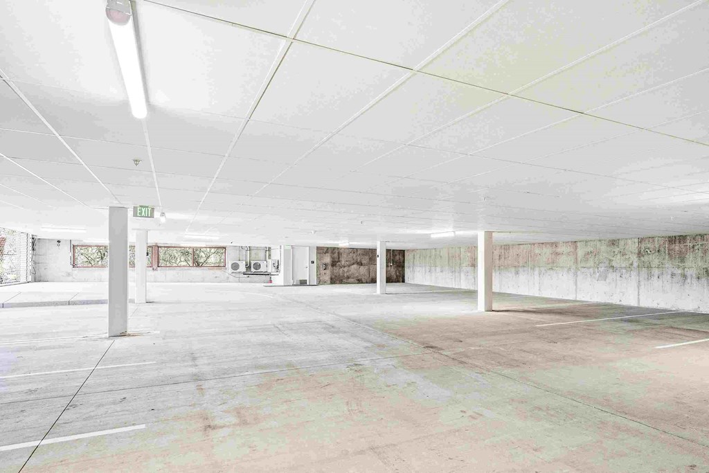 an empty parking garage with white ceilings and concrete floors
