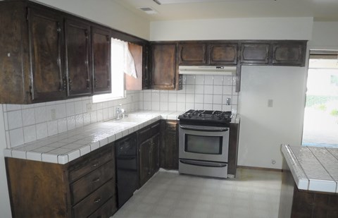 an empty kitchen with dark wood cabinets and a silver stove