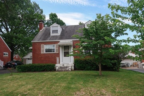 A red brick house with a white door and a small porch.
