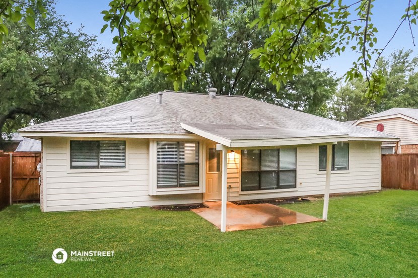 a small white house with a porch and a tree
