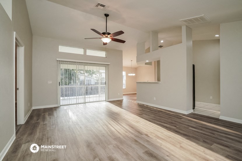 an empty living room with a ceiling fan