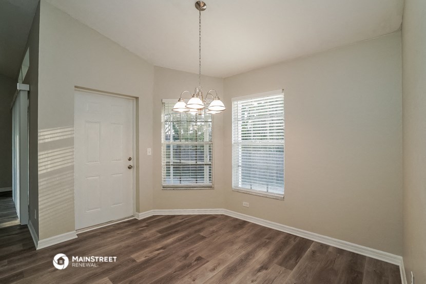 the spacious living room of a house with a door and window