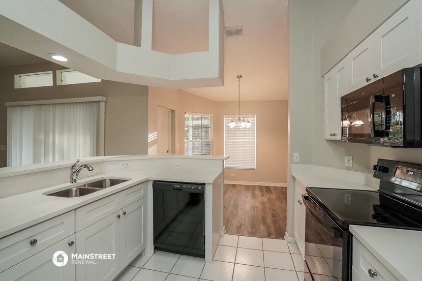 a kitchen with white cabinets and black appliances