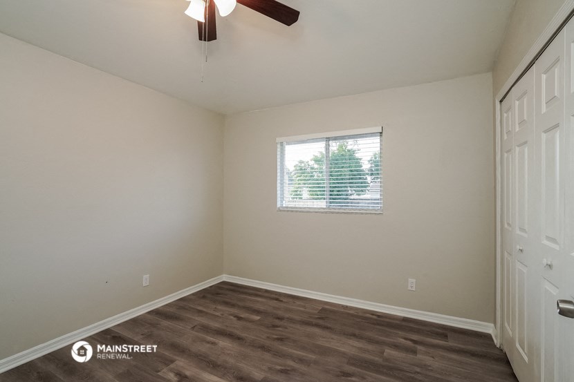the interior of a bedroom with a window and a ceiling fan