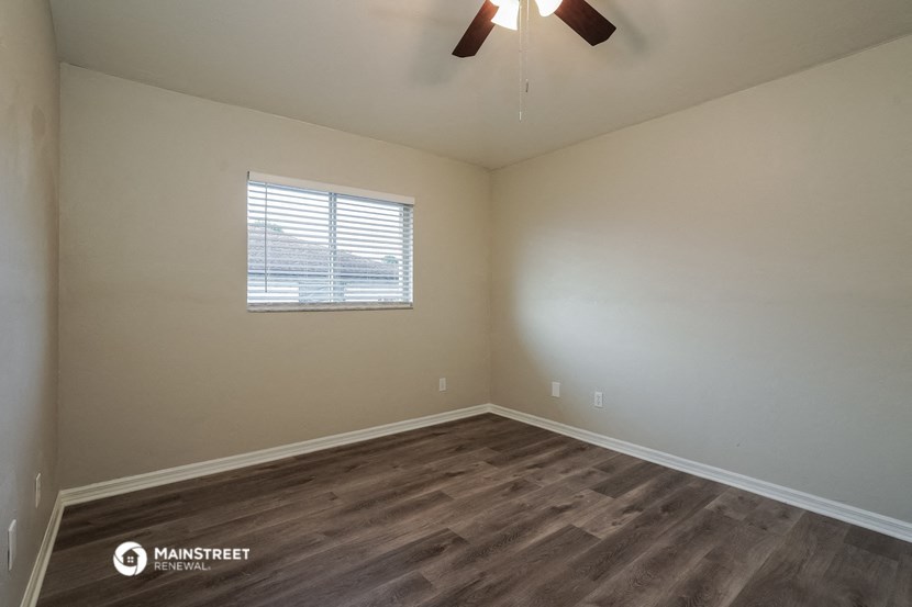 the interior of a bedroom with wood flooring and a window