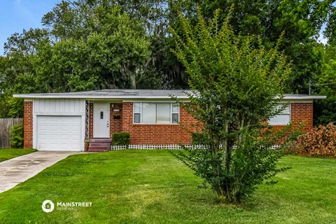 a small brick house with a tree in front of it