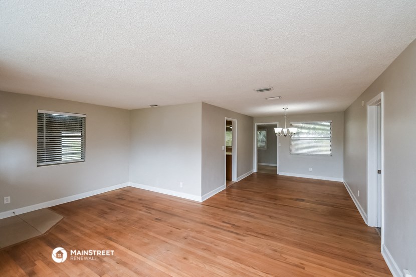 an empty living room with wood floors and white walls