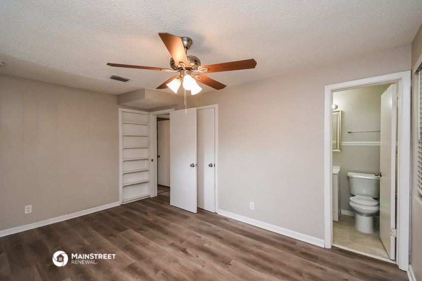 a living room with a ceiling fan and a closet and a toilet