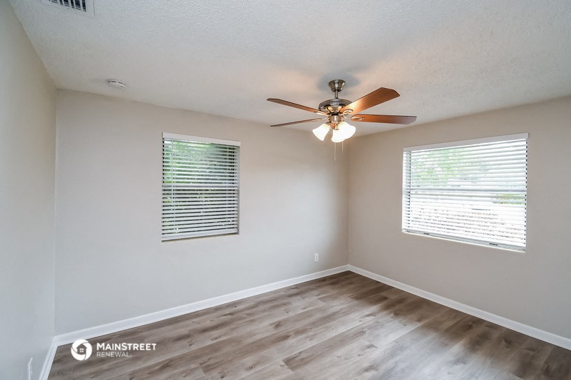 the spacious bedroom has a ceiling fan and a window