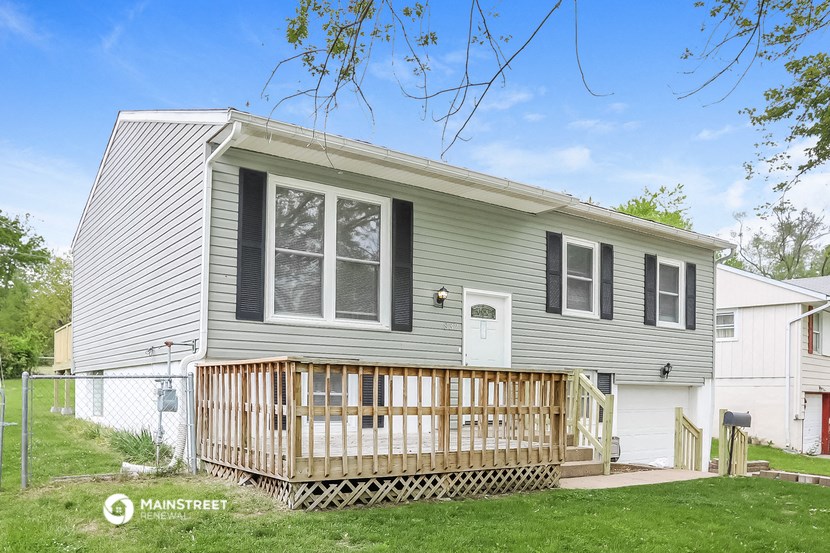 a gray house with a porch and a white fence
