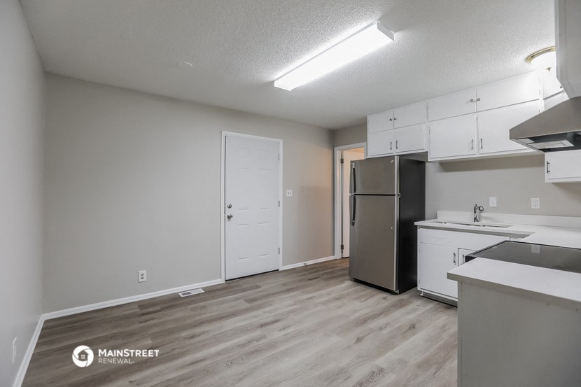 an empty kitchen with white cabinets and a stainless steel refrigerator