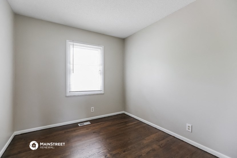 the living room of an apartment with wood flooring and a window