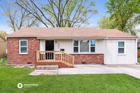 a small brick house with a porch and a deck