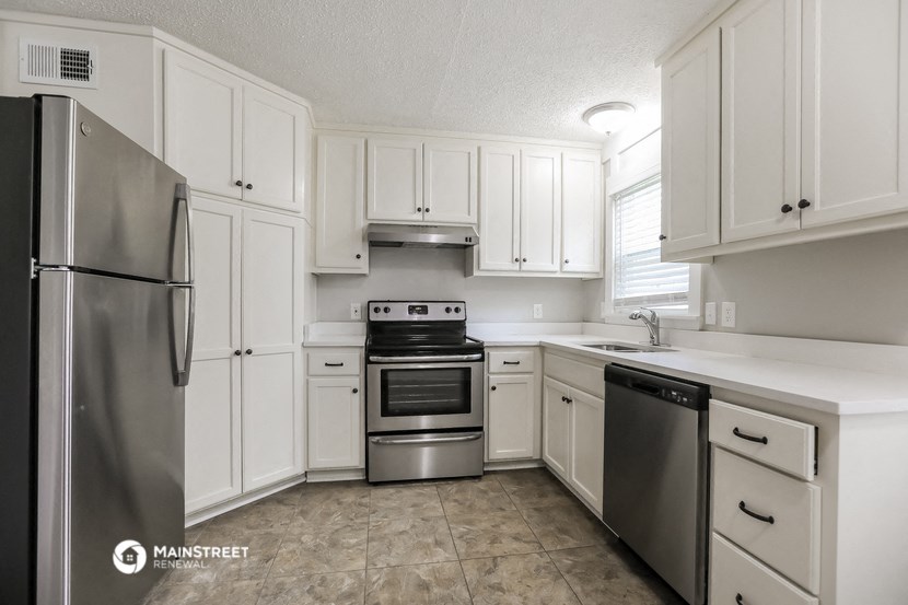 a white kitchen with stainless steel appliances and white cabinets