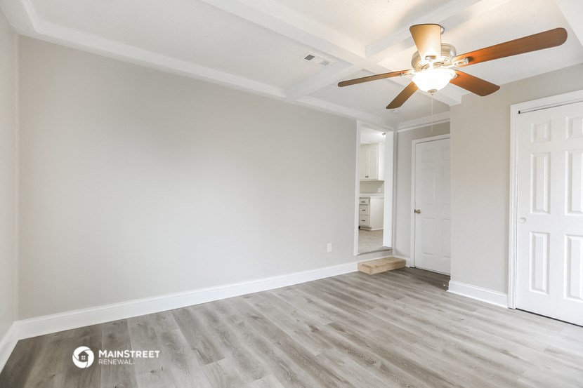 a living room with a ceiling fan and a door to a bathroom