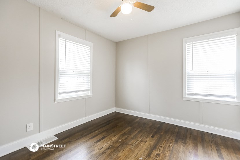 the living room of an apartment with wood floors and a ceiling fan