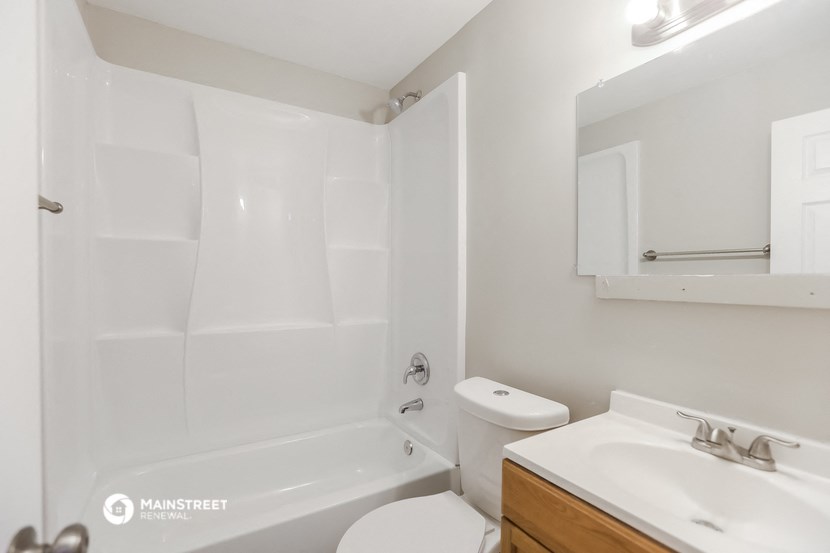 a bathroom with a toilet sink and tub and a mirror