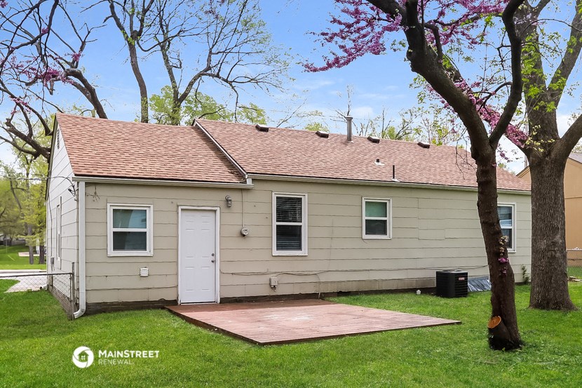 a small tan house with a porch and a white door