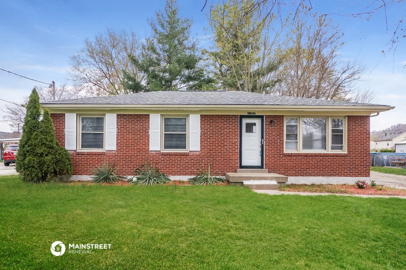 a small brick house with a white door and a lawn