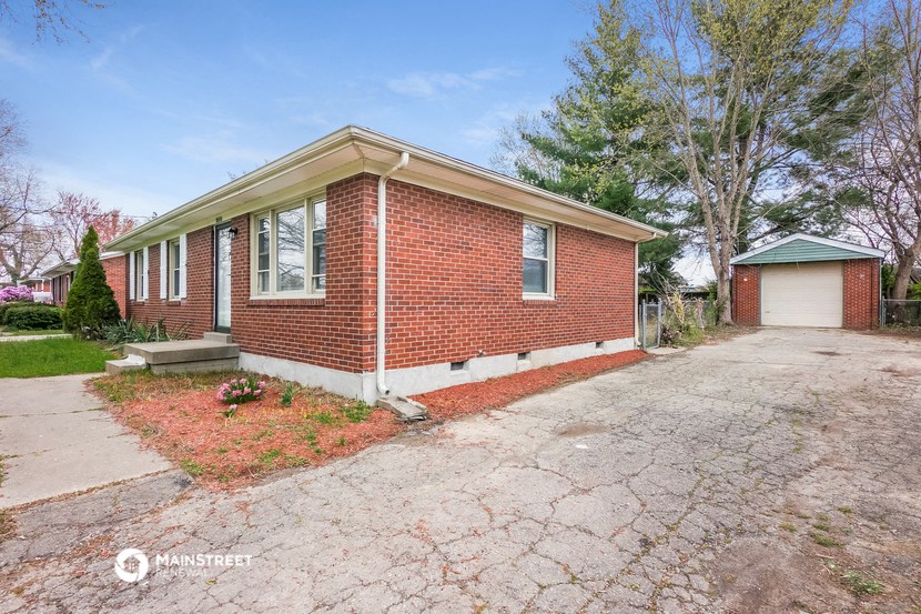 a small brick house with a driveway and a white garage door