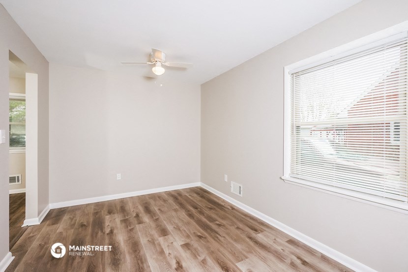 the spacious living room with a large window and wood flooring