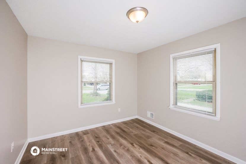 the spacious living room with hardwood flooring and two windows