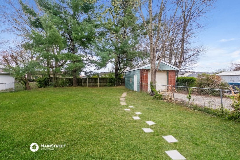 a yard with a chain link fence and a small shed