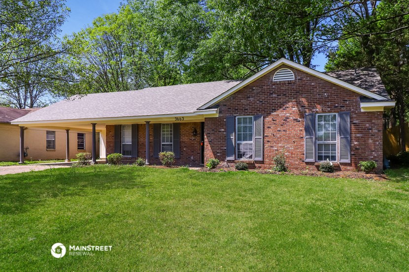 a small brick house with a green lawn and trees